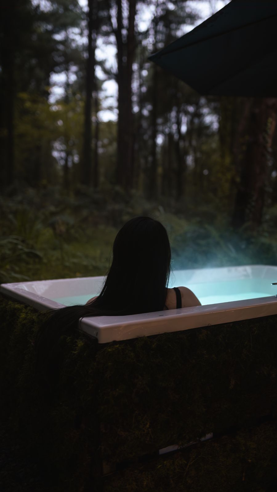 Guest relaxing in the steaming hot tub among the trees