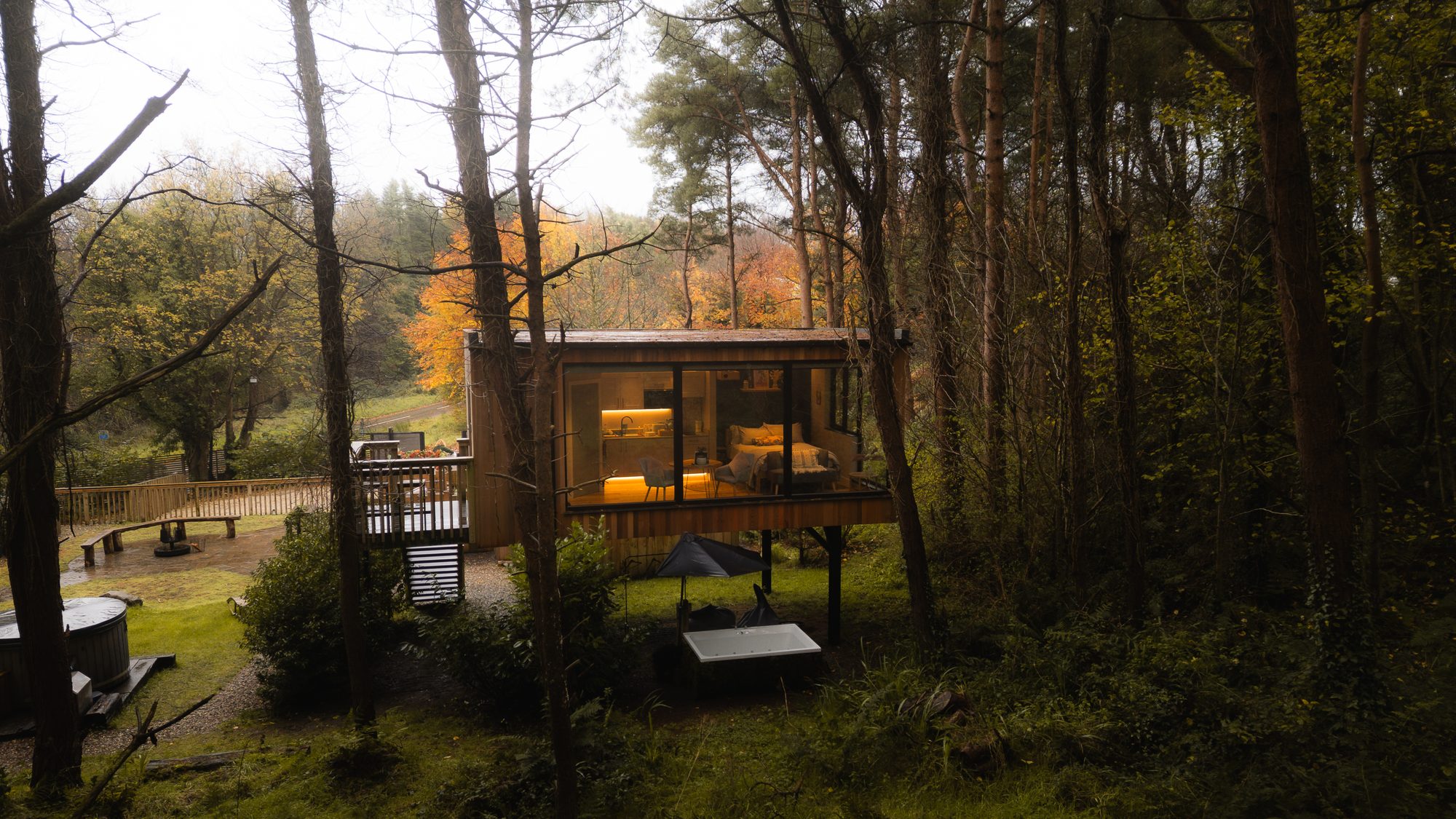 Burrenmore Nest cabin glowing among autumn pines