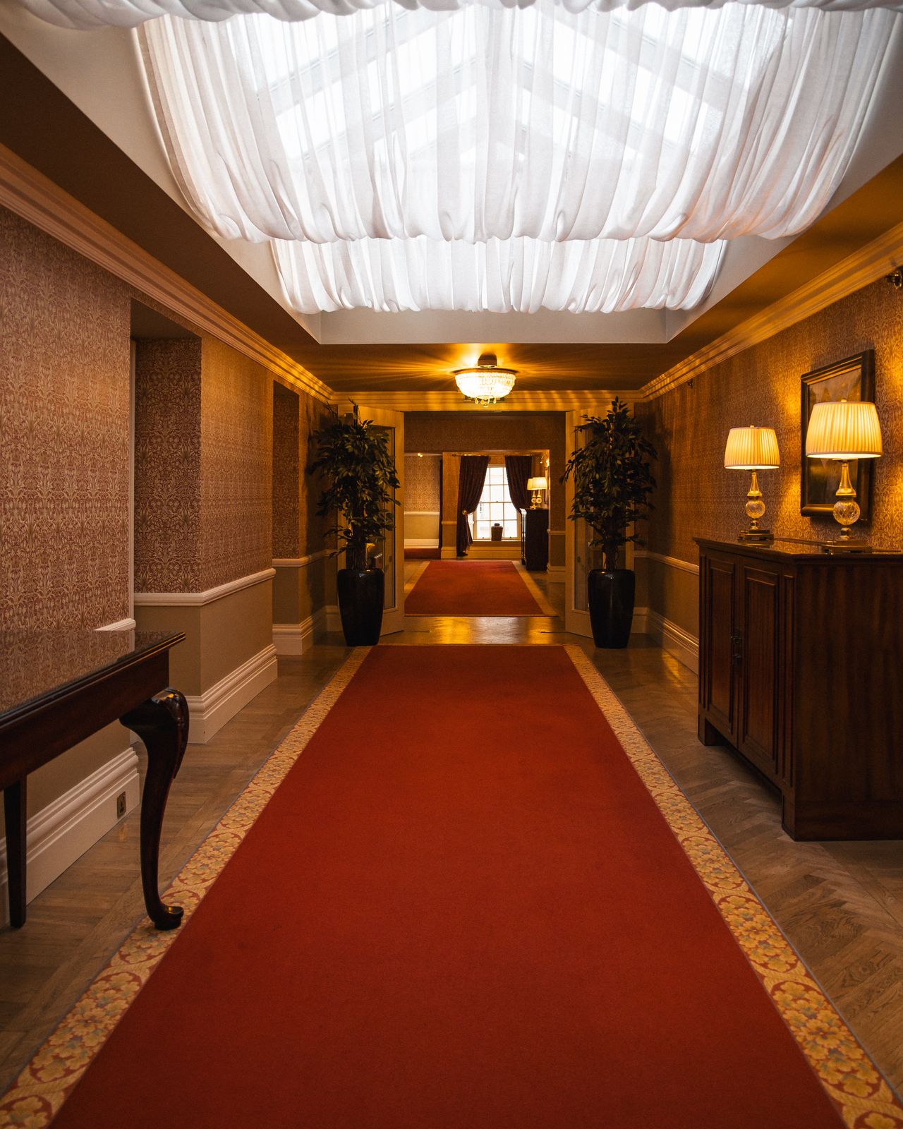 Long corridor with a red carpet runner and warm lamplight