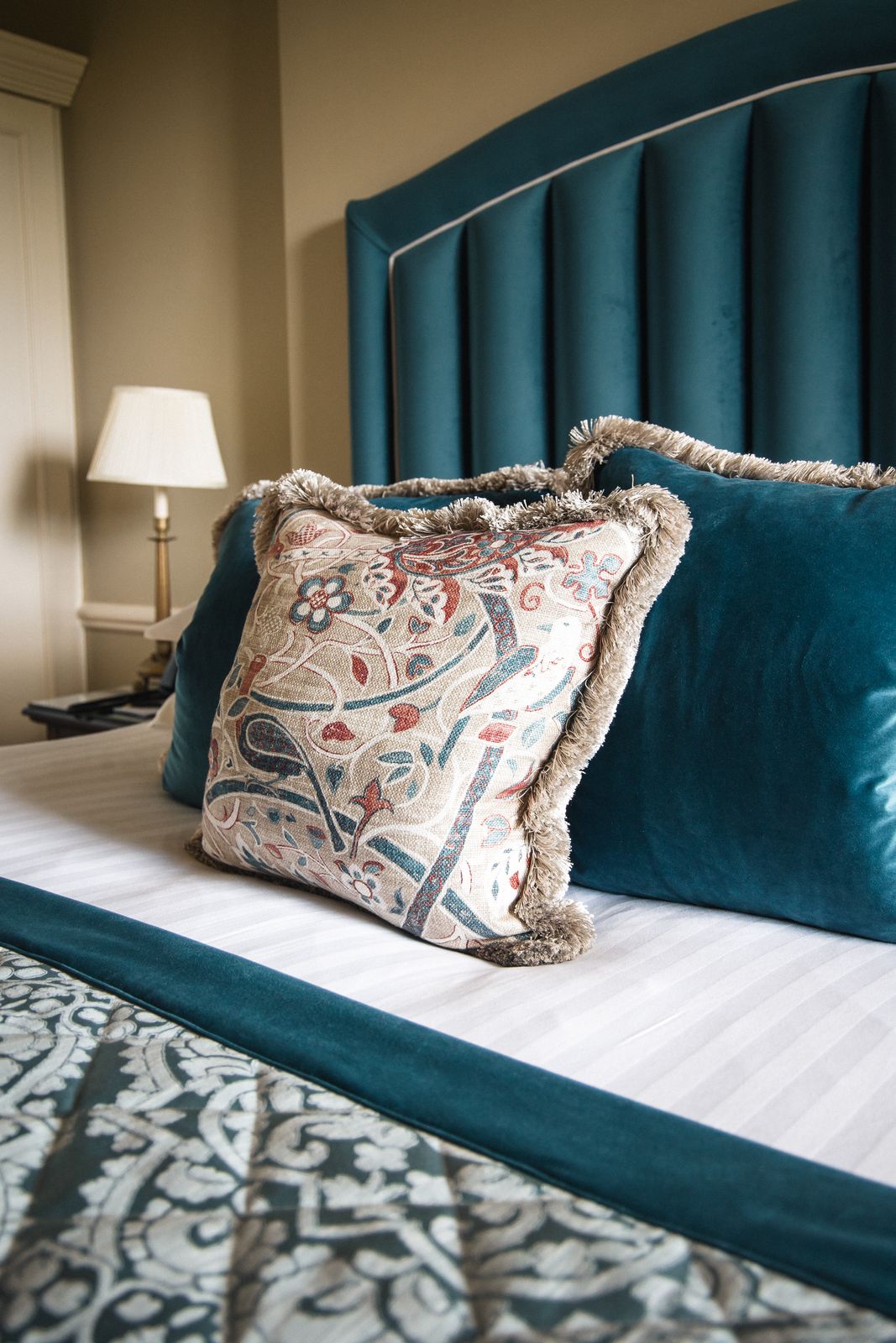 Embroidered cushion detail against velvet and crisp linen