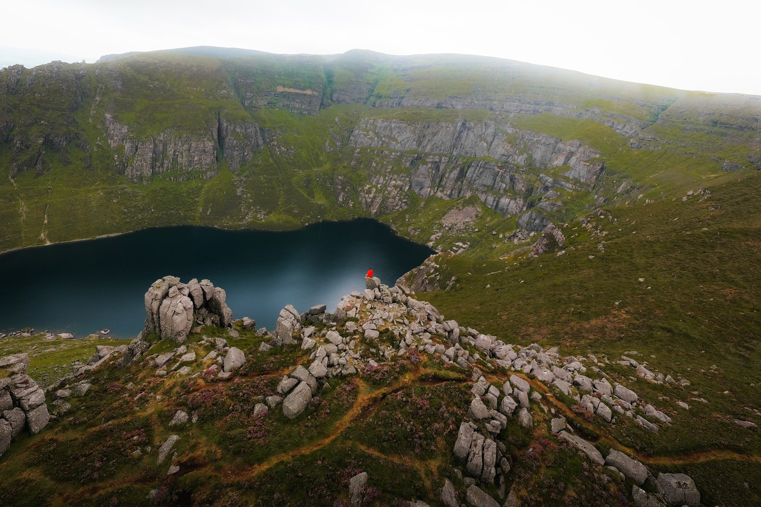 A dark corrie lake below cliffs, seen from the ridge