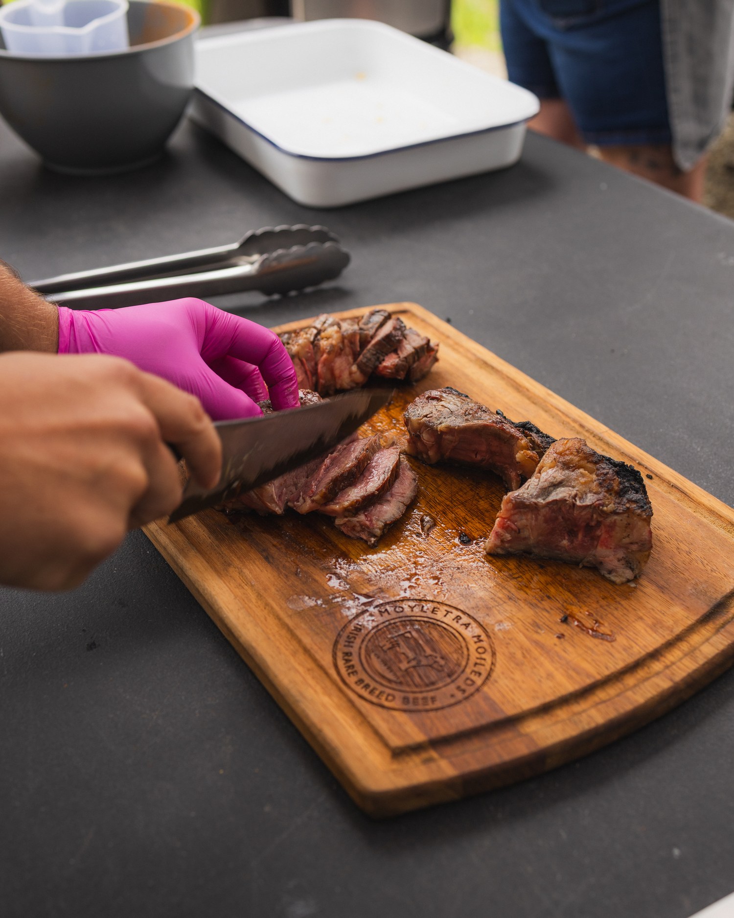 A chef slicing cooked meat on a wooden board