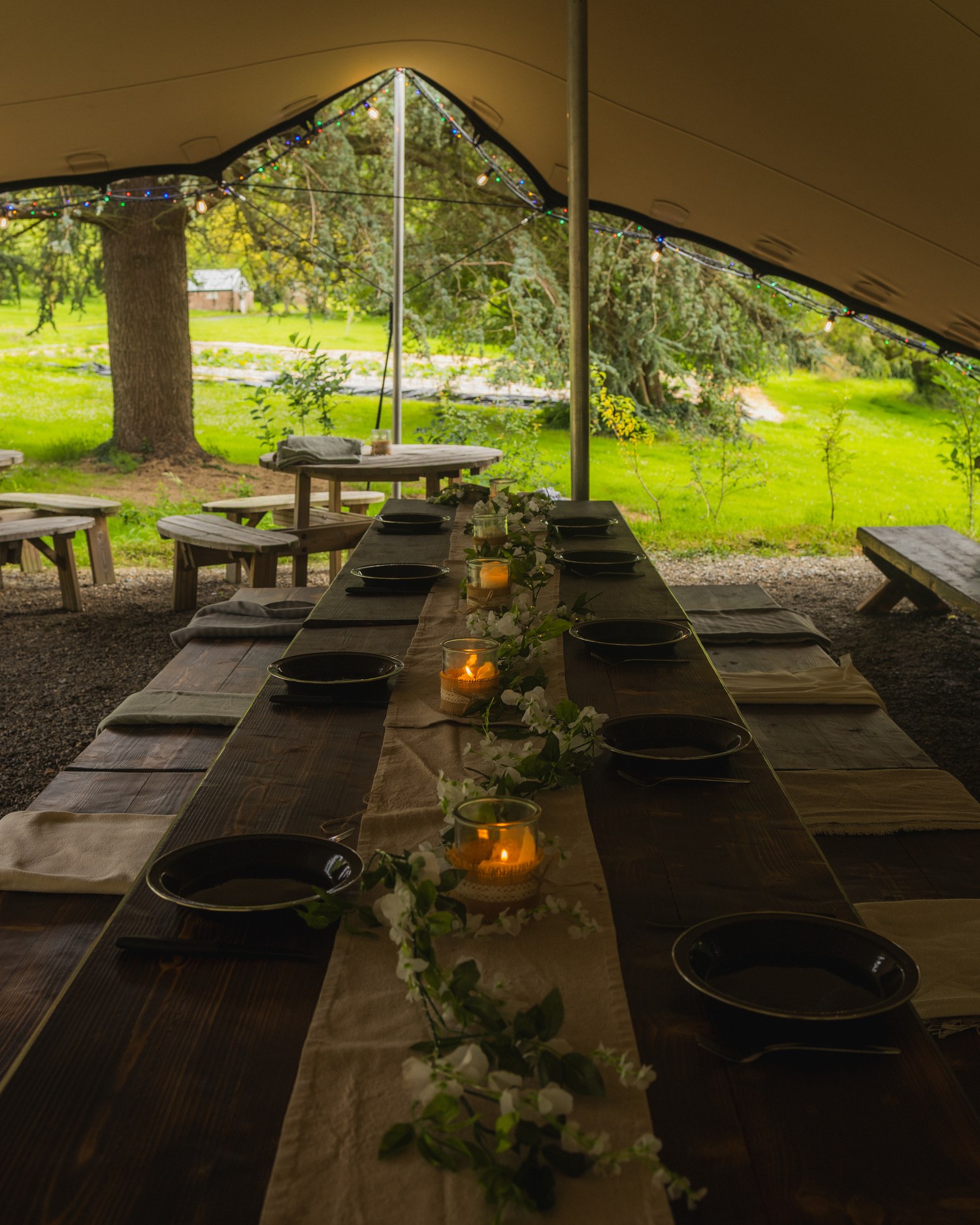 A long table set under an open sided tent at dusk