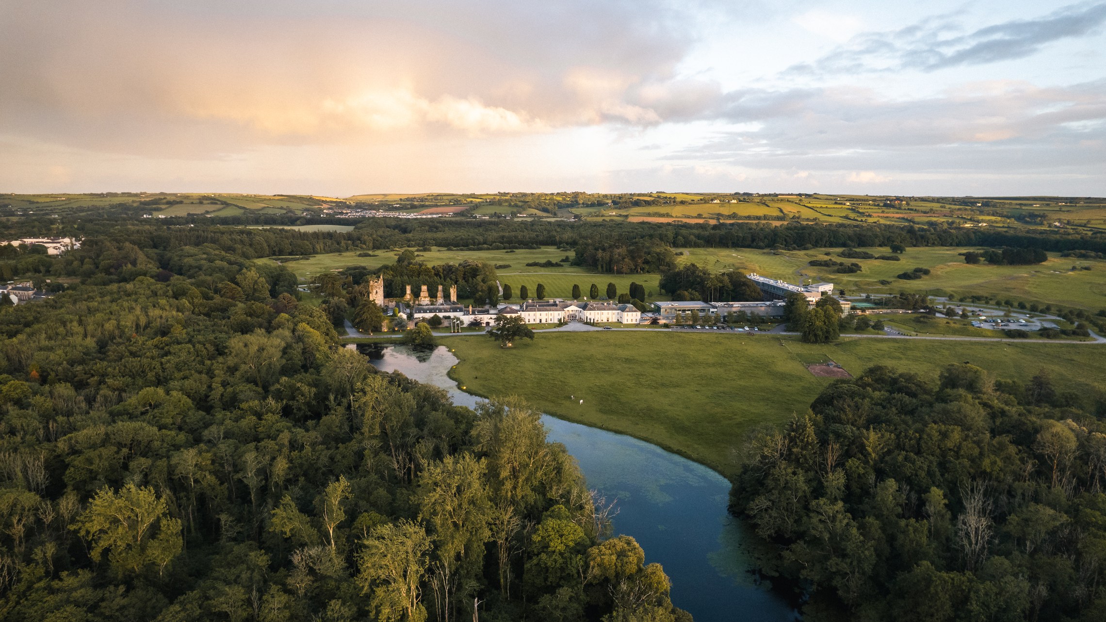 A river winding past a country estate at dusk, seen from above