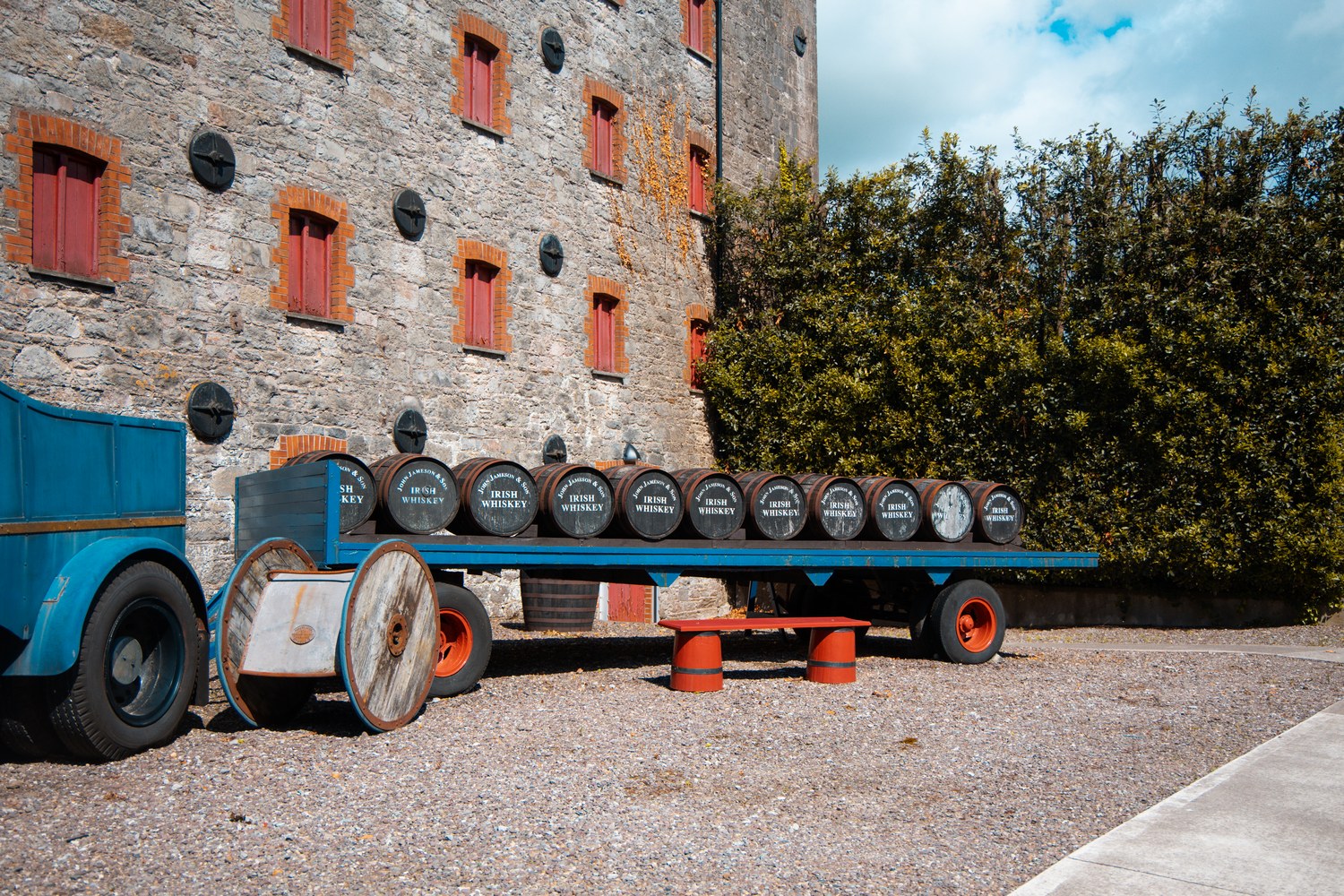 Distillery casks stacked on a flatbed beside a stone warehouse