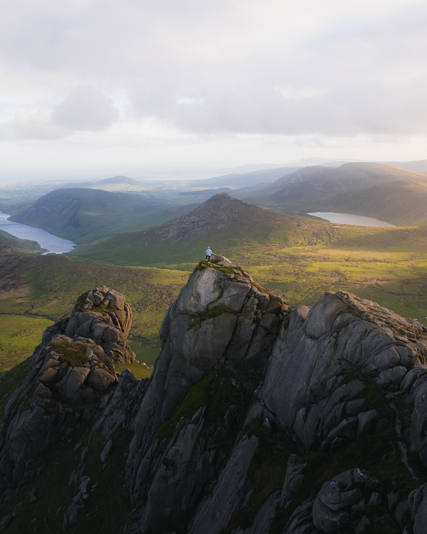 A walker seated on a granite tor above a mountain valley