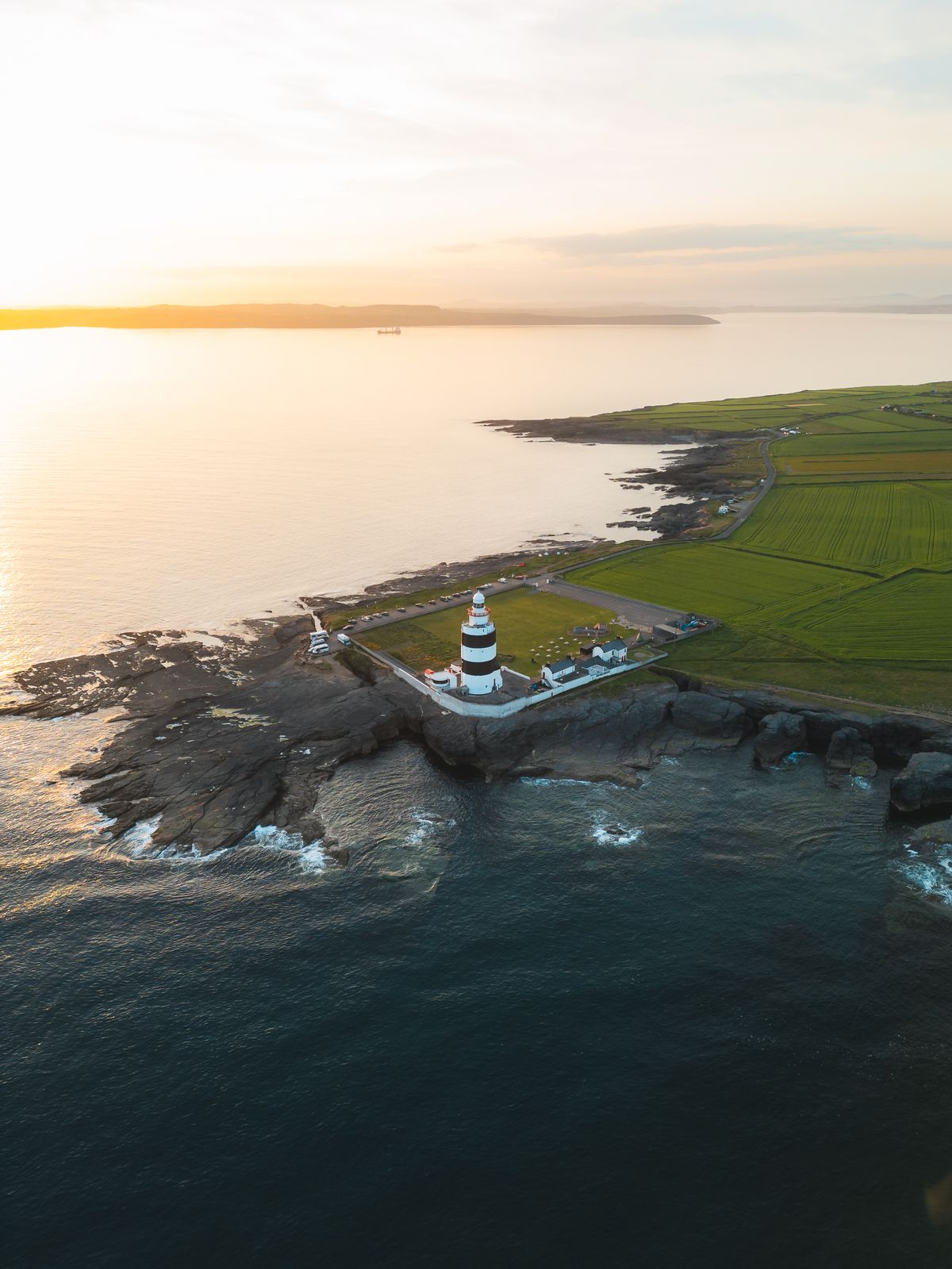 Lighthouse on a headland at sunset from above