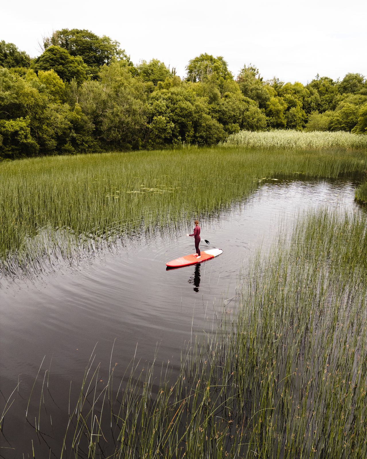 Guest paddleboarding across still water at Finn Lough