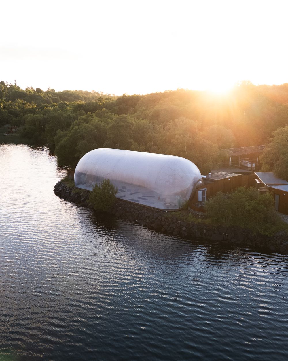 A Finn Lough bubble dome glowing at sunset beside the lake, Fermanagh