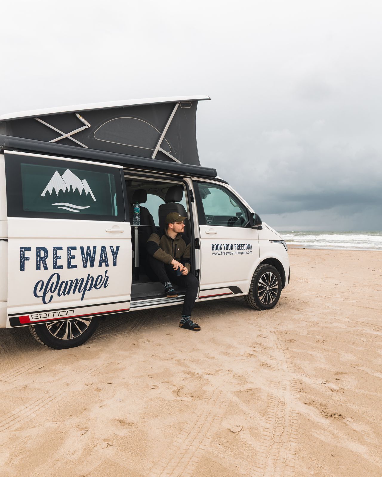 Camper van on the sand with the roof tent up
