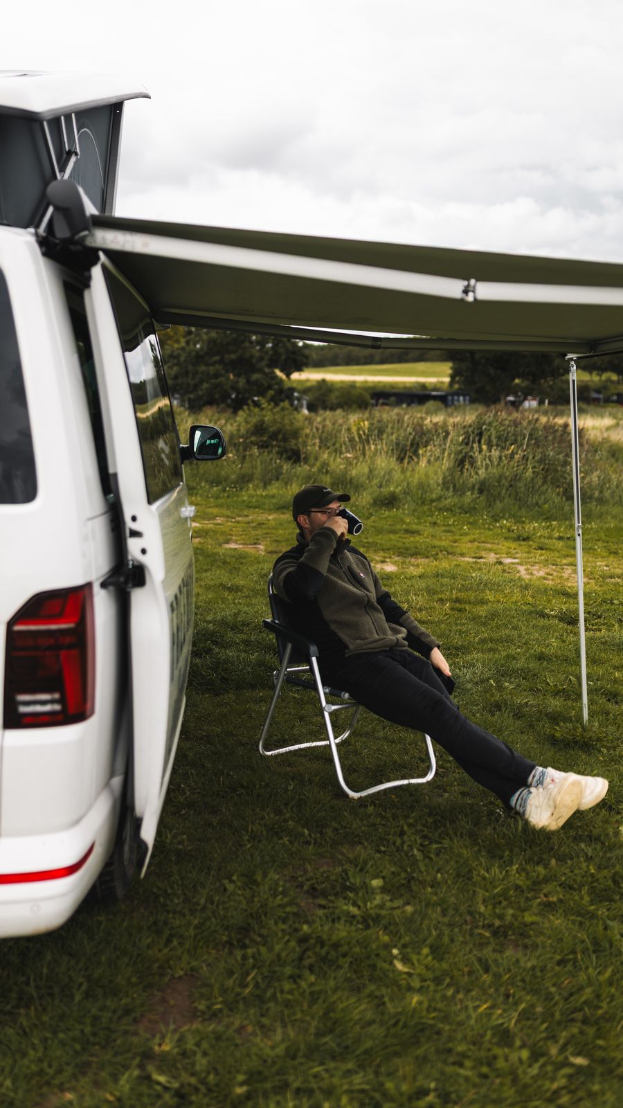 Traveller relaxing in a chair under the van awning