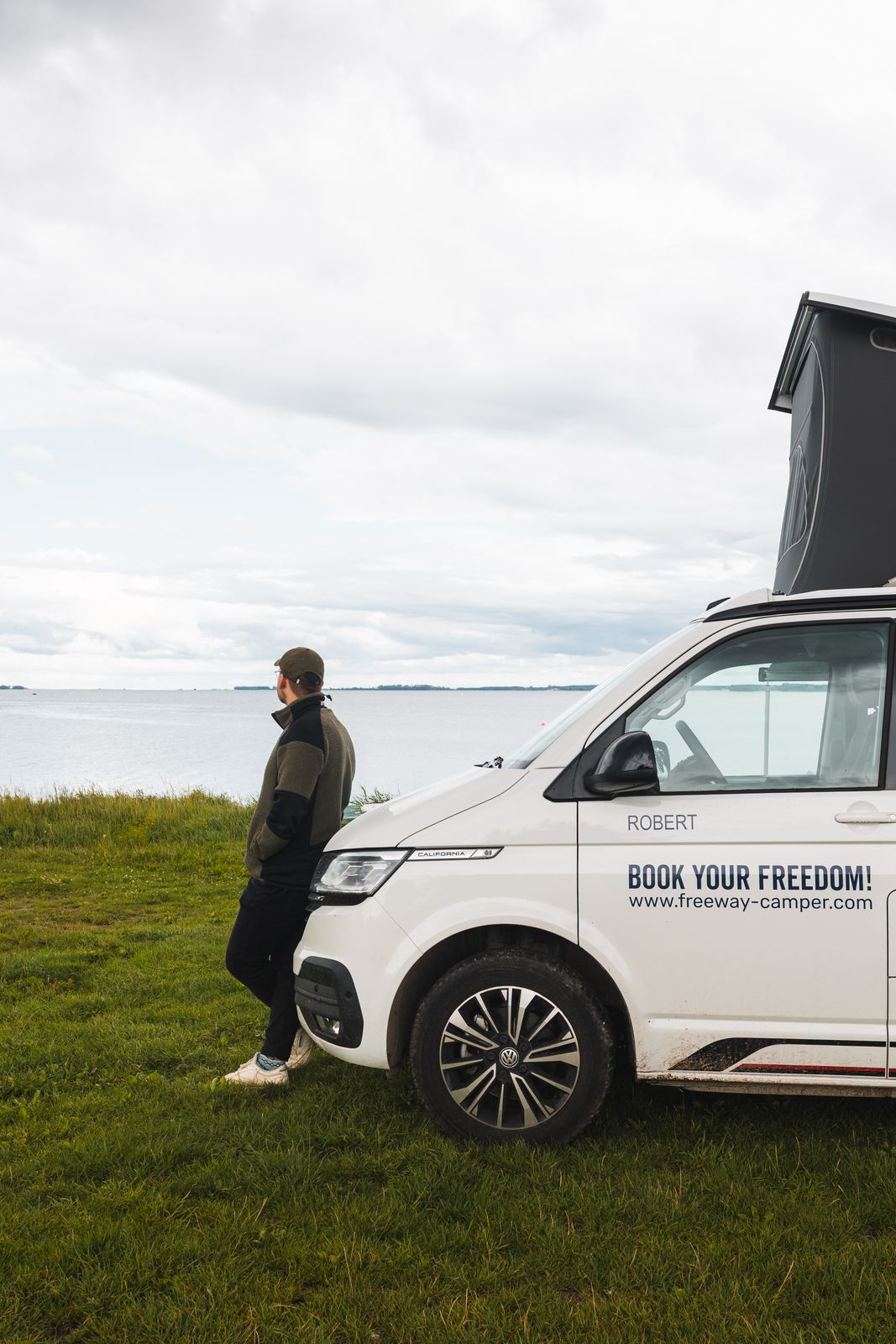 Traveller standing beside the van in an open field