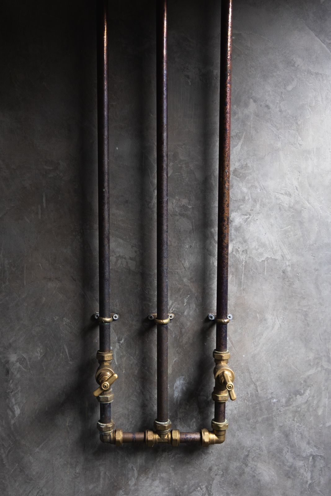 Exposed brass pipework against bare plaster