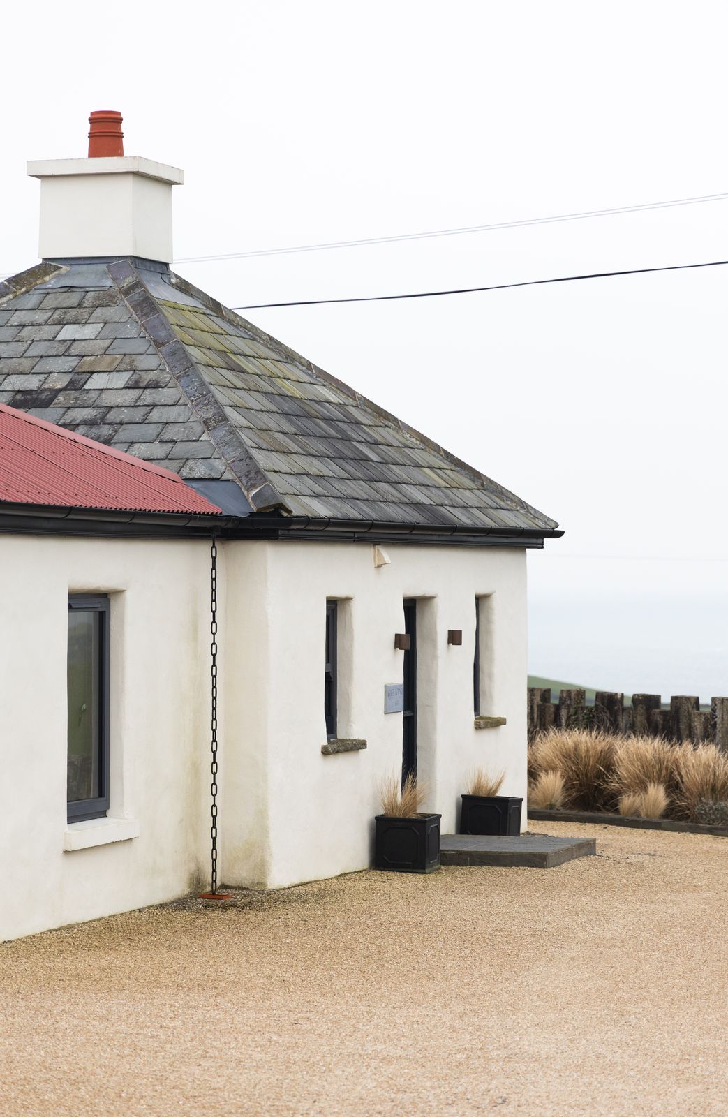 Whitewashed cottage exterior with a red roofline