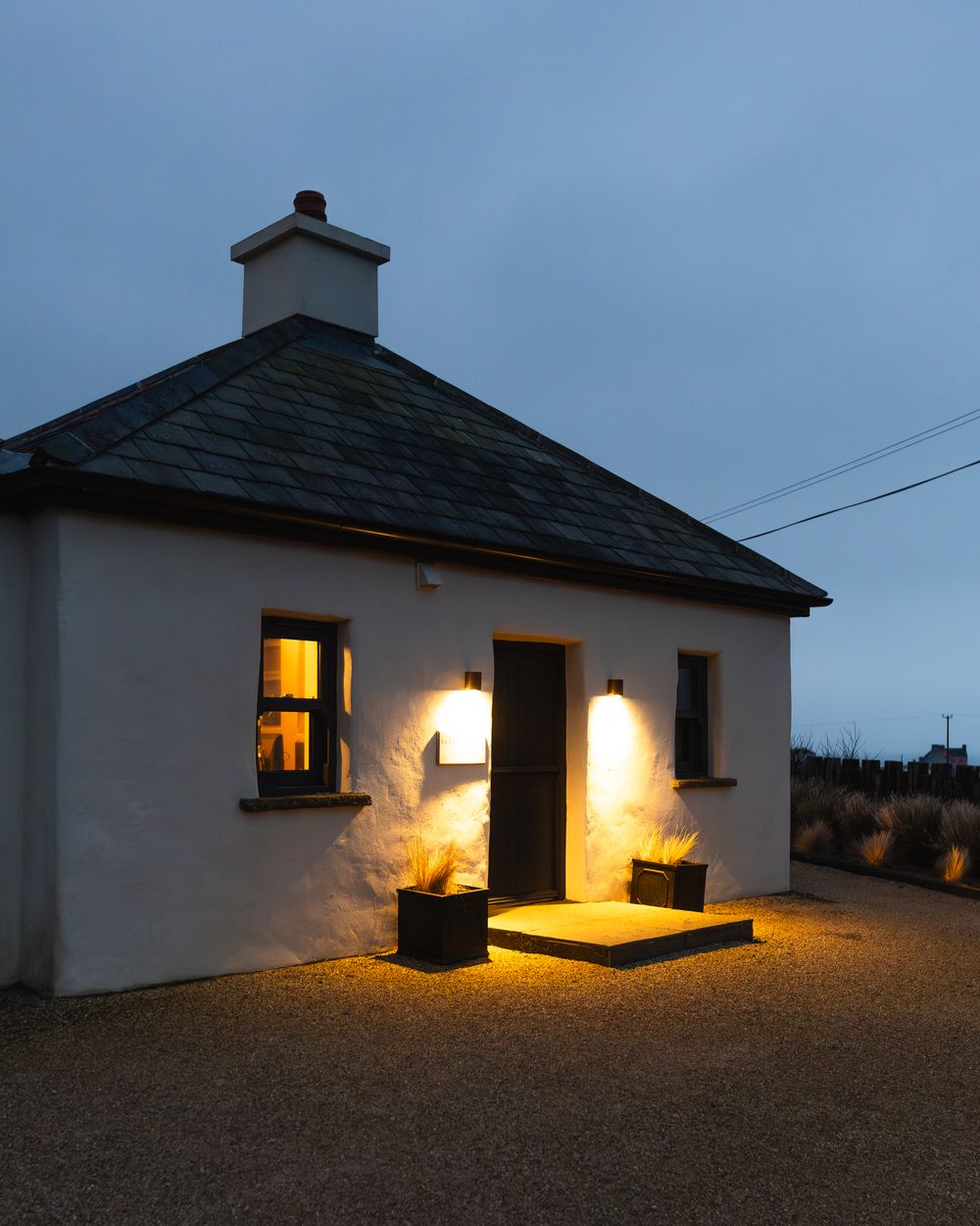 Gate Lodge 1837 lit from within at blue hour on the Clare coast