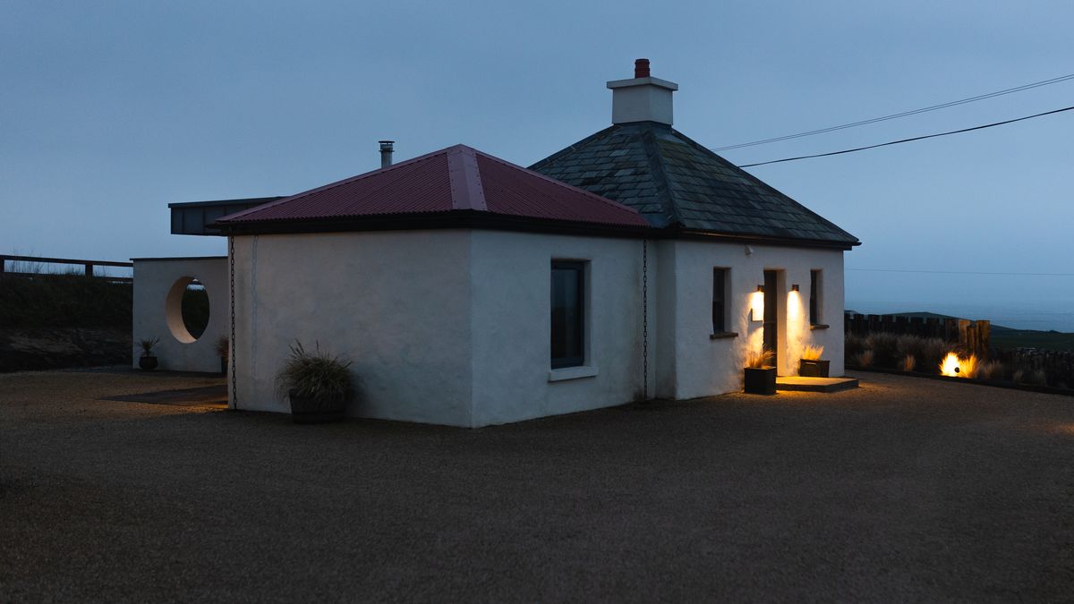 Gate Lodge 1837 lit from within at blue hour on the Clare coast