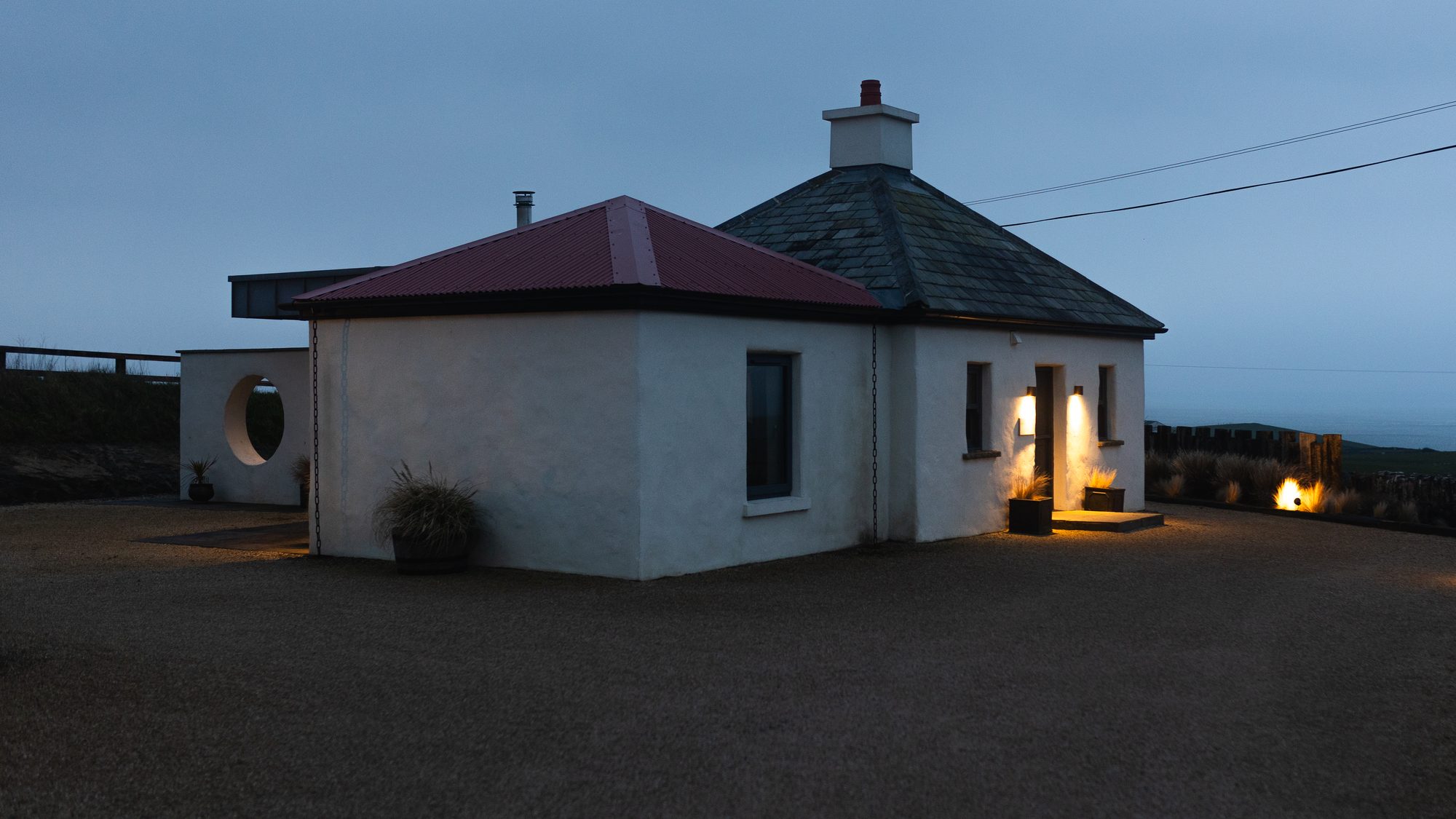 Gate Lodge 1837 lit from within at blue hour on the Clare coast