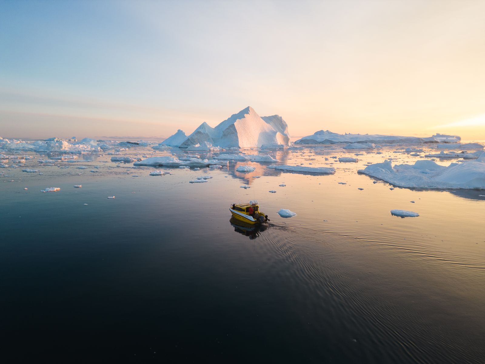 Boat wake cutting through icy water at dusk