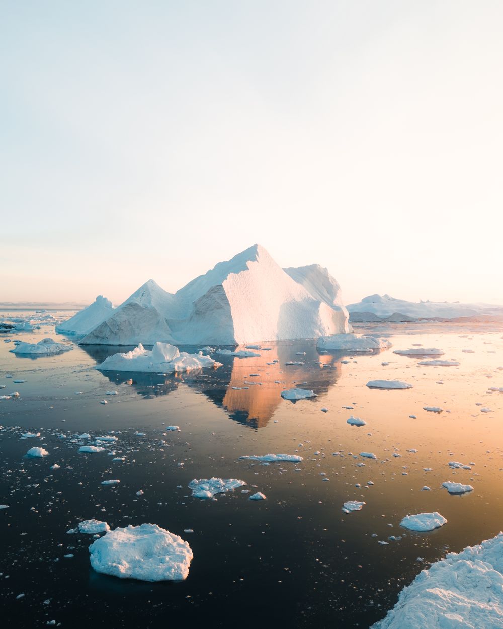 Small boat dwarfed by towering icebergs in the Ilulissat Icefjord