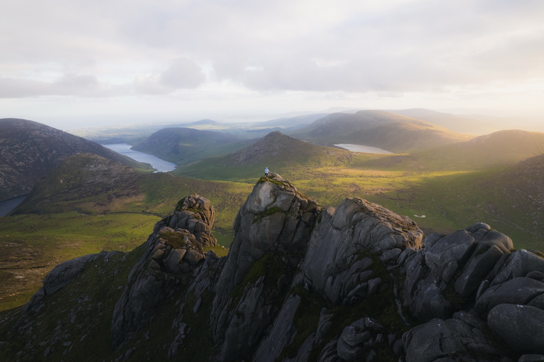 A hiker on the granite tor summit of Slieve Bearnagh in the Mourne Mountains, County Down