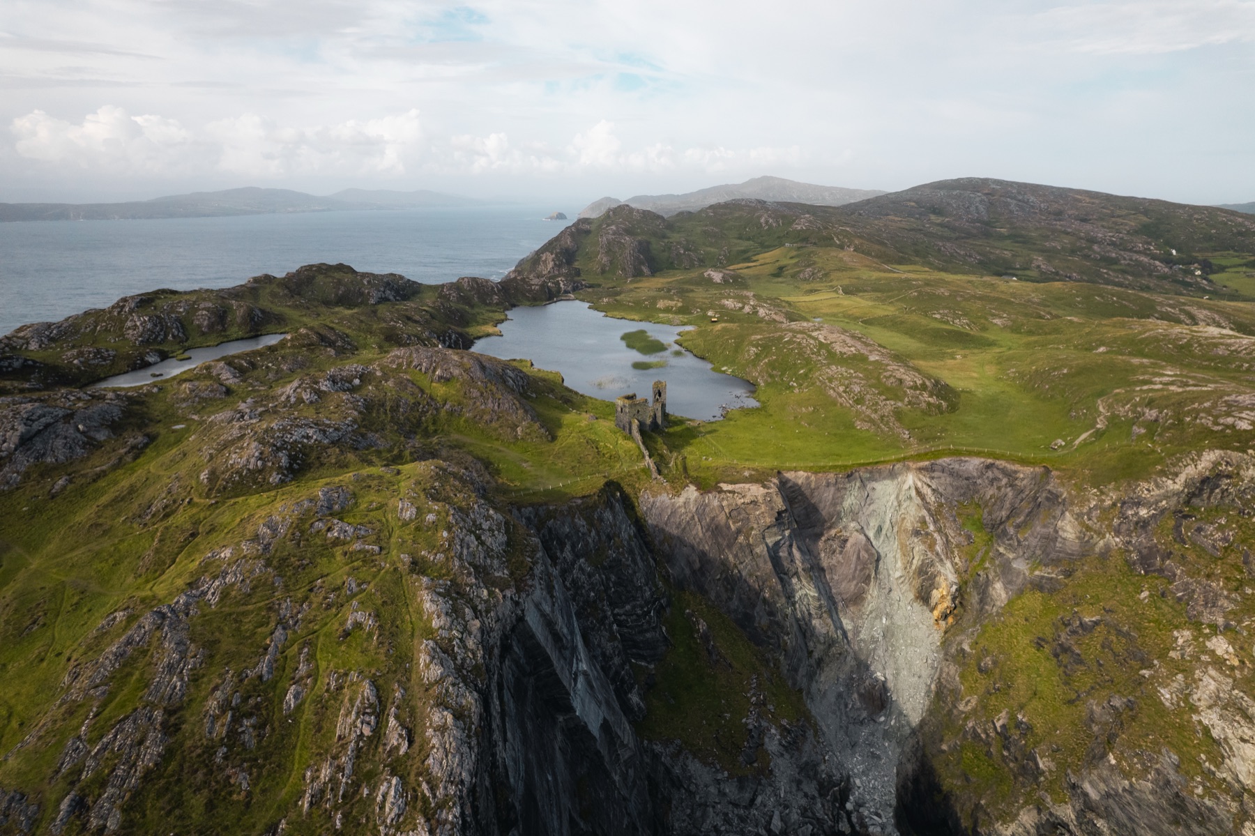 The ruined towers of Dunlough Castle above the lake at Three Castle Head, County Cork