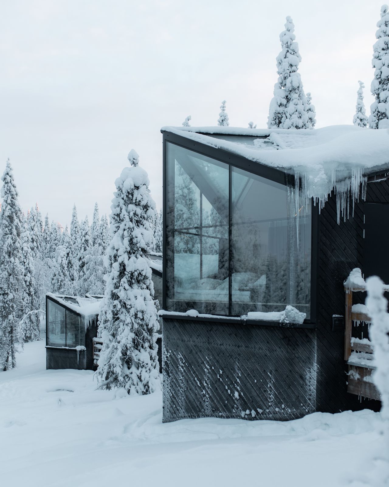 The glass cabin exterior surrounded by snow covered forest