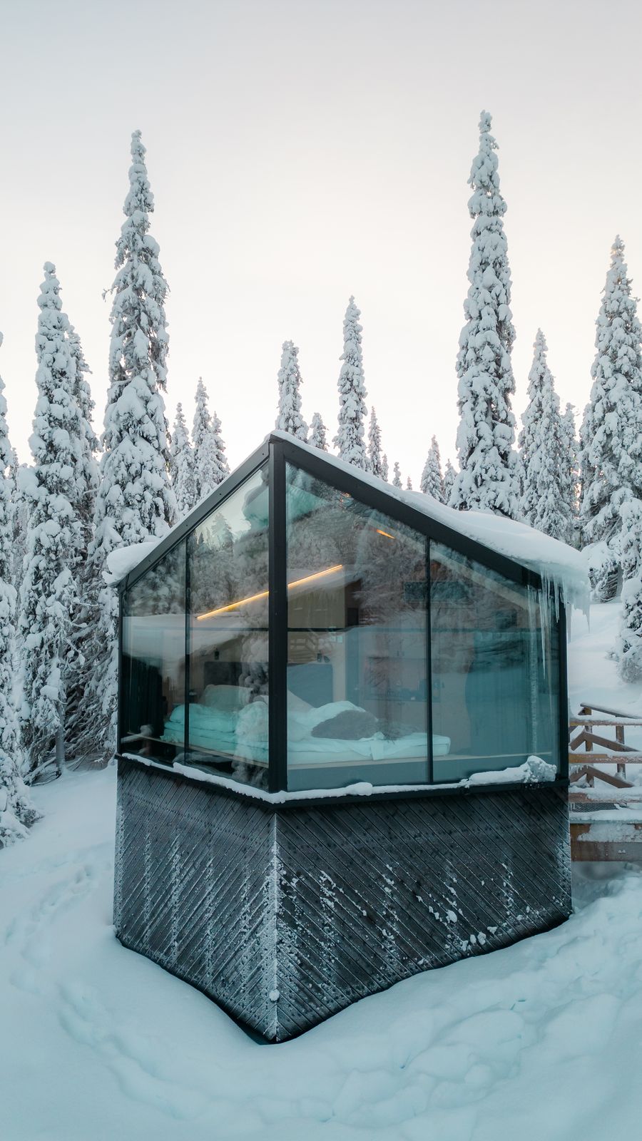 The cabin at dusk with its interior light spilling onto snow