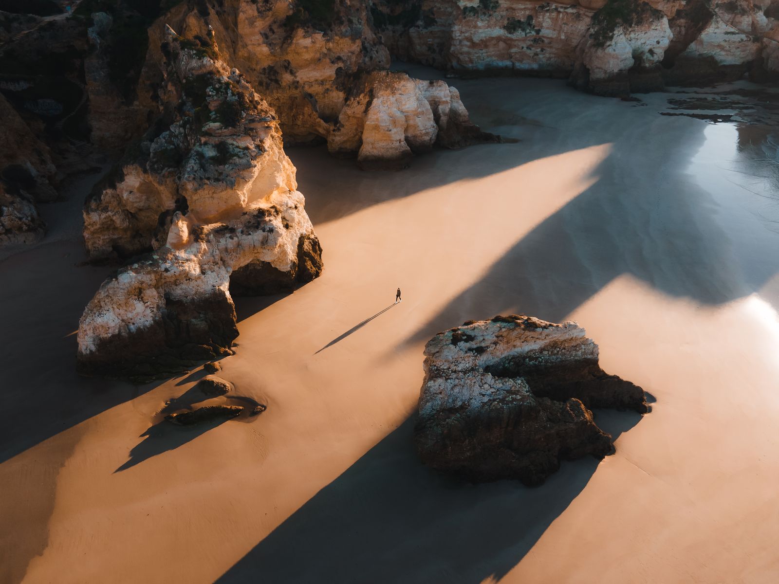 Rock stacks casting long shadows on the sand