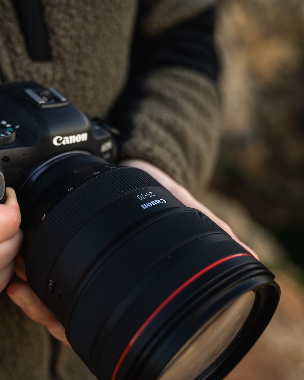 Canon camera and telephoto lens held in hand, close up