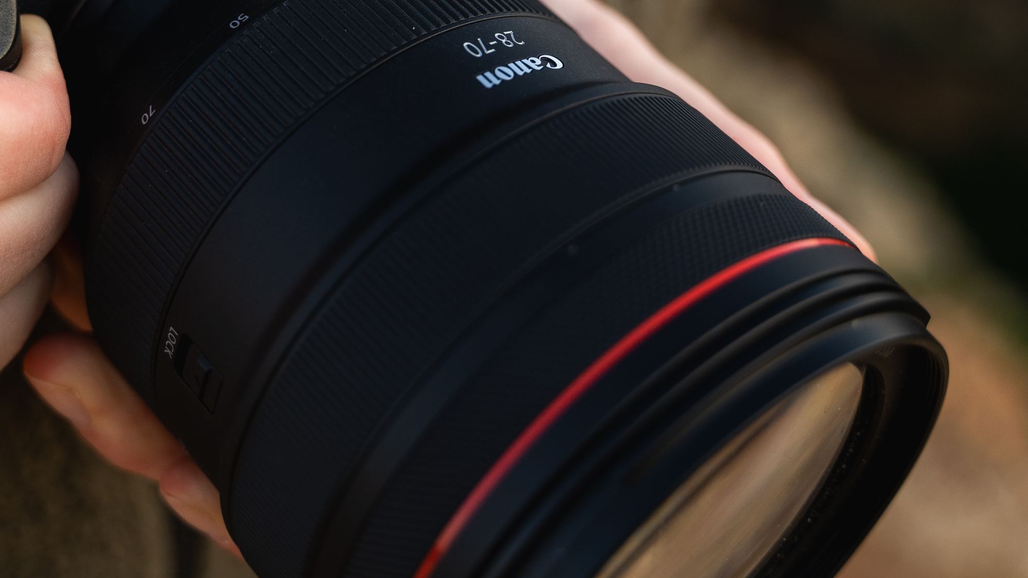 Canon camera and telephoto lens held in hand, close up