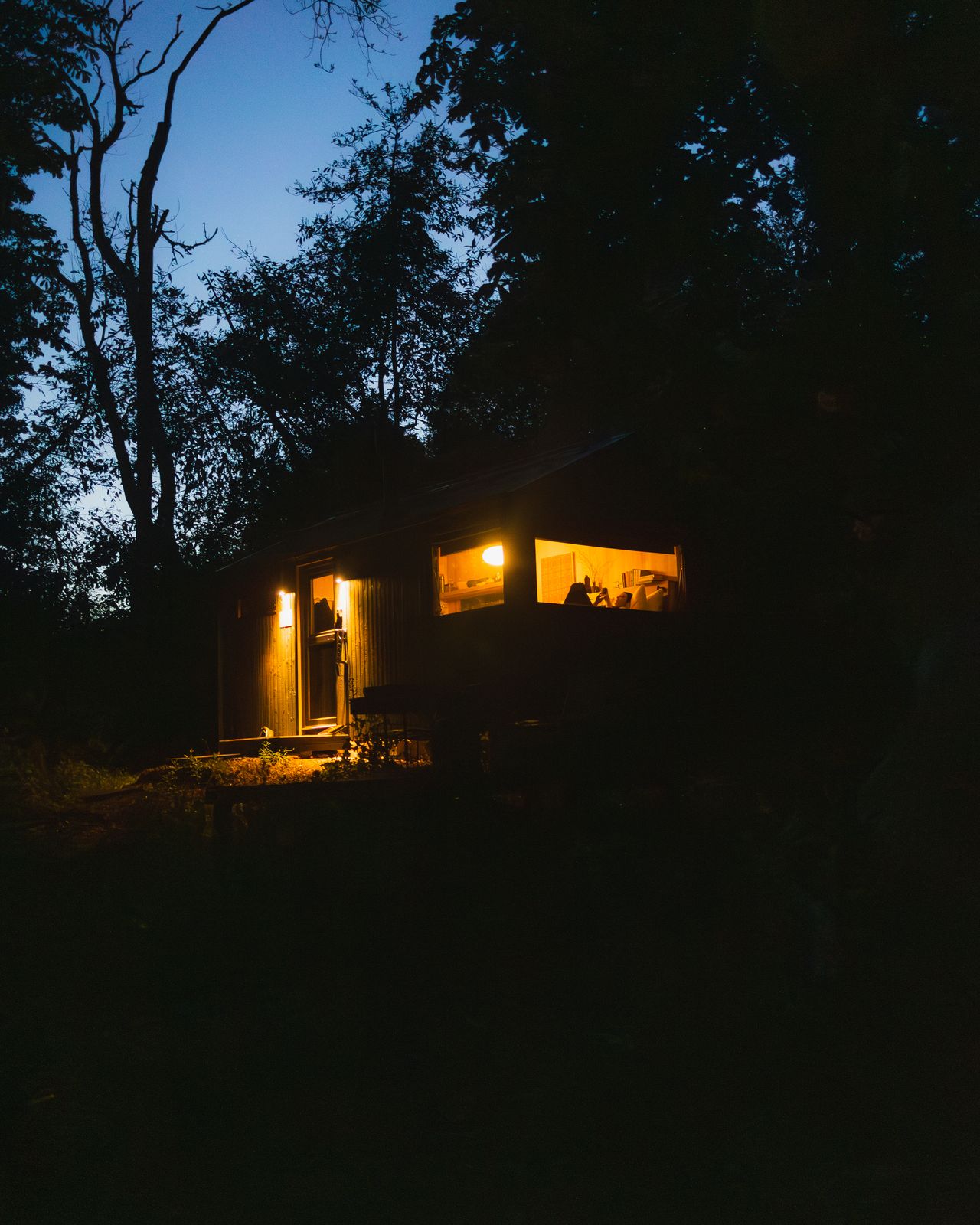 The cabin at blue hour with its windows glowing