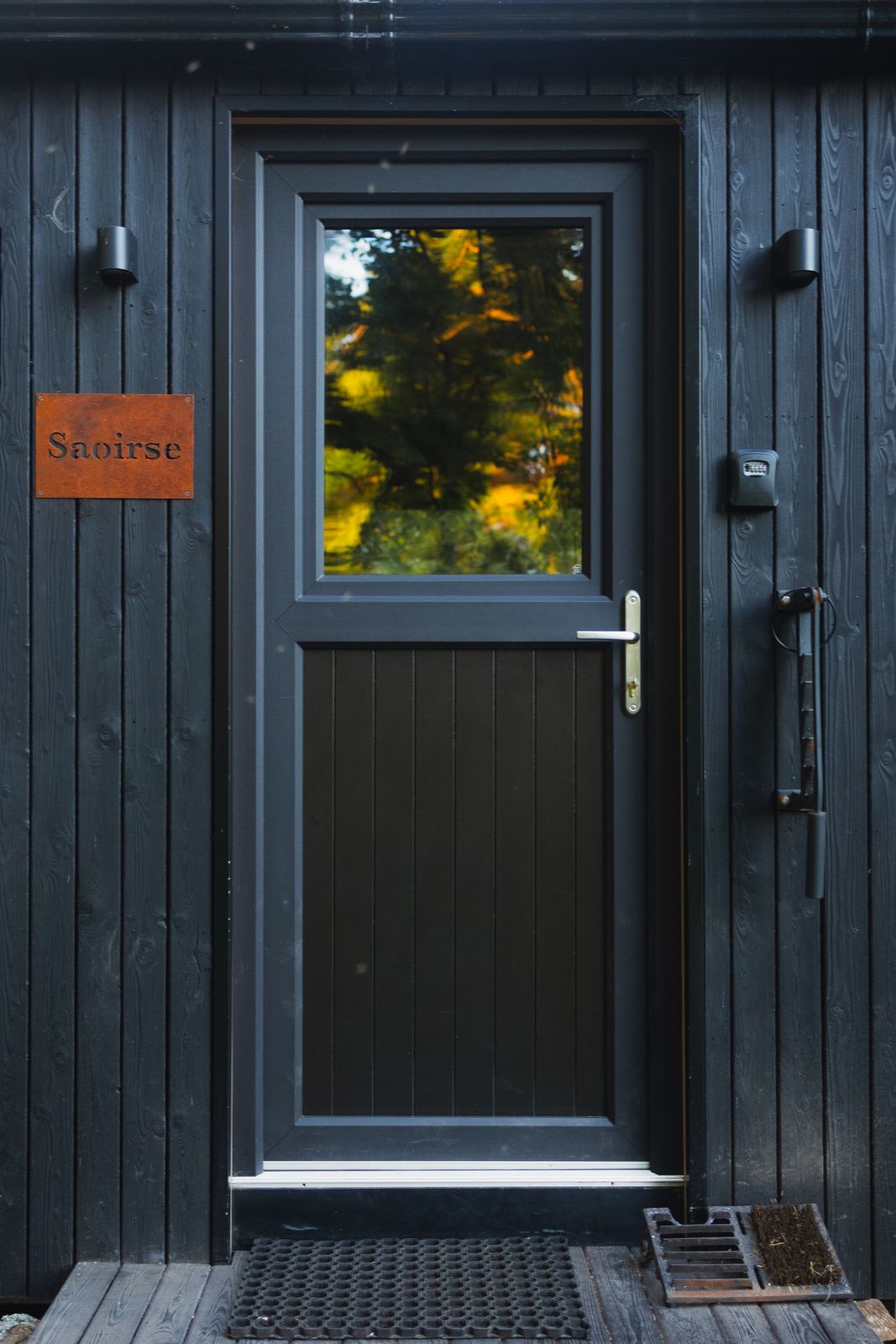 Black timber entrance door with a name plate